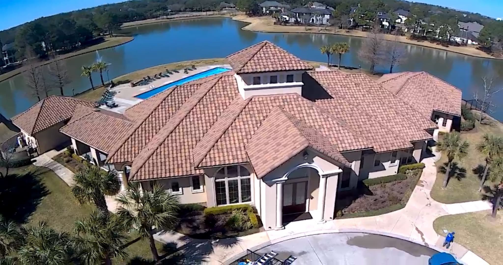 Aerial view of red clay tile roof cleaning at a lakeside community clubhouse in Houston, TX by XLR8 Pressure Washing Services